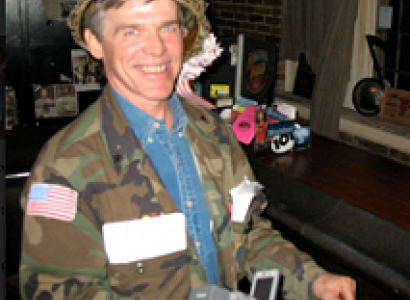 White man with a helmet on a big smile, and a camouflage jacket
