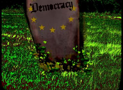 Tombstone that says Democracy on it in a grassy field