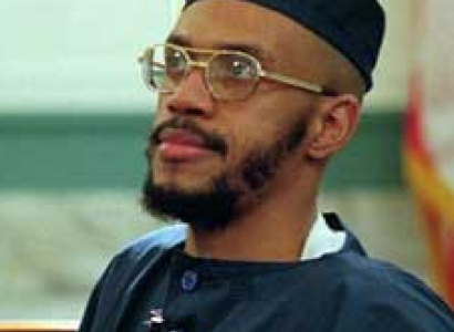 Black man  with wire-rimmed glasses and a mustache and beard