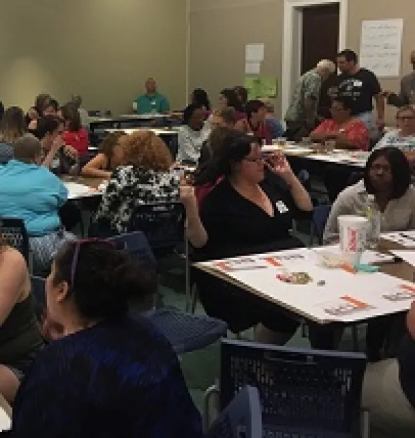 Lots of diverse people sitting at tables in a big room