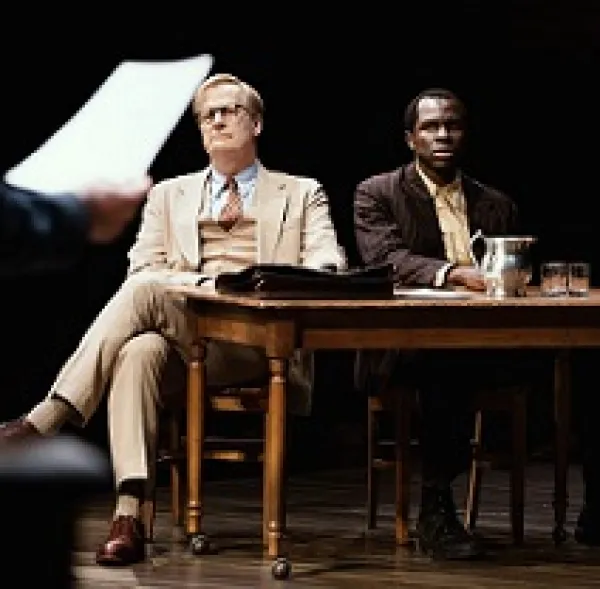 White man and black man sitting at a table looking very solemn