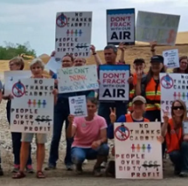 Many people posing outside holding signs about the environment