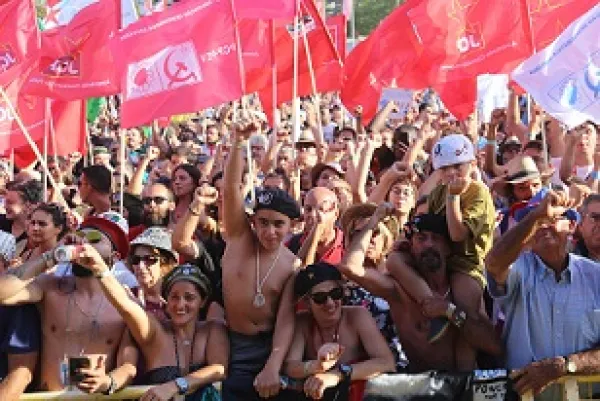 Hundreds of people outside waving lots of red flags