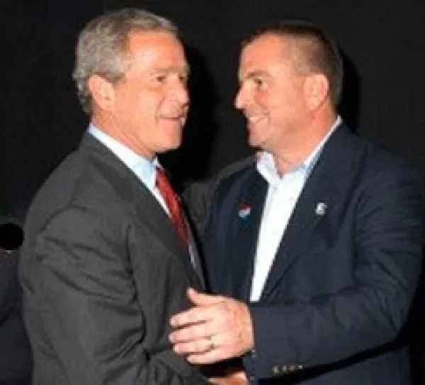 Two middle aged white men shaking hands very close together