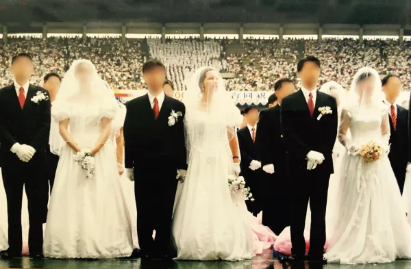 Two couples, grooms in black suits and women in long white wedding dresses