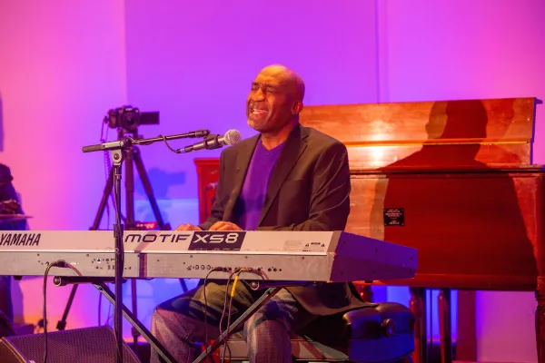 Bald black man singing at a keyboard
