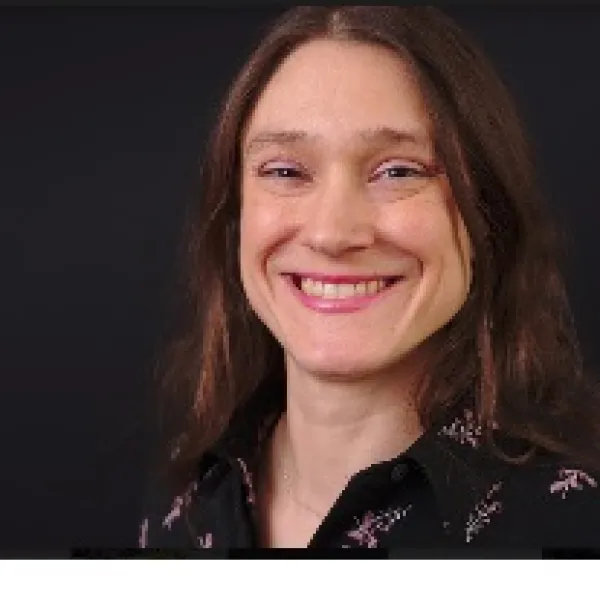 Youngish white woman with straight brown hair smiling at the camera