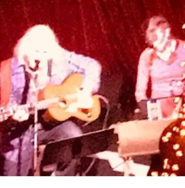 Two guys on stage one playing guitar