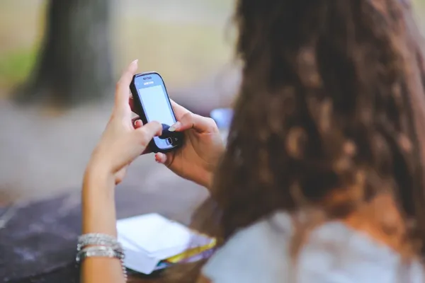 Side view of girl with brown curly hair looking at cellphone