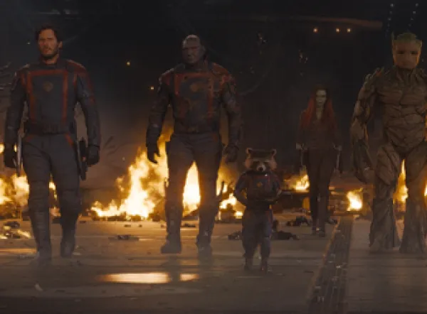 Character walking in formation with fire in the background