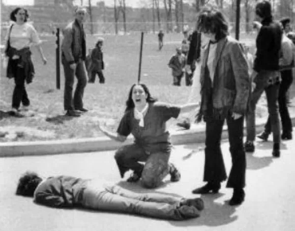 Man lying on the ground dead a woman screaming over his body, others looking on