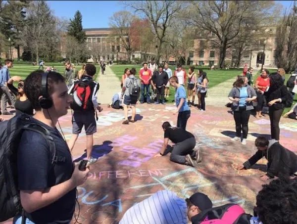 Students coloring with chalk on the Oval to cover up hate speech