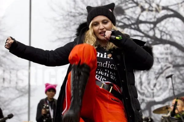 Madonna in orange pants and black bots dancing outside