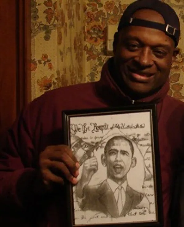 Black man smiling and holding an illustration of Obama