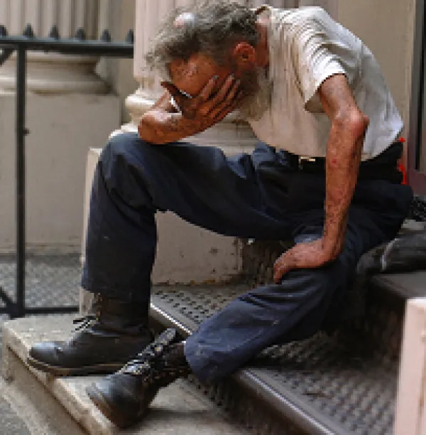 Man with head in hand in despair sitting outside on stairs