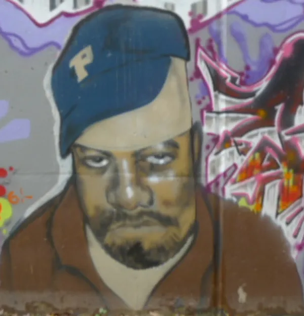 A black man wearing a blue baseball cap looking sad