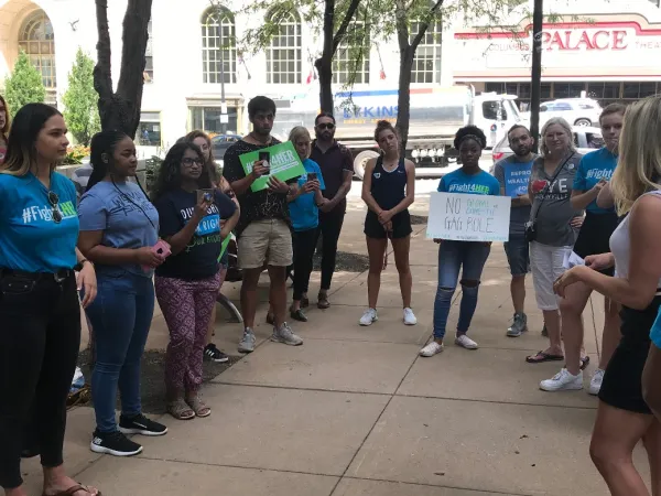 Students standing outside holding signs on a city street