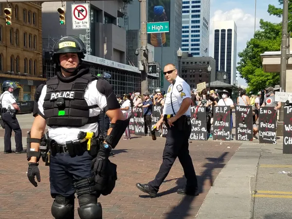 Protestors with shields as police in riot gear prepare for attack