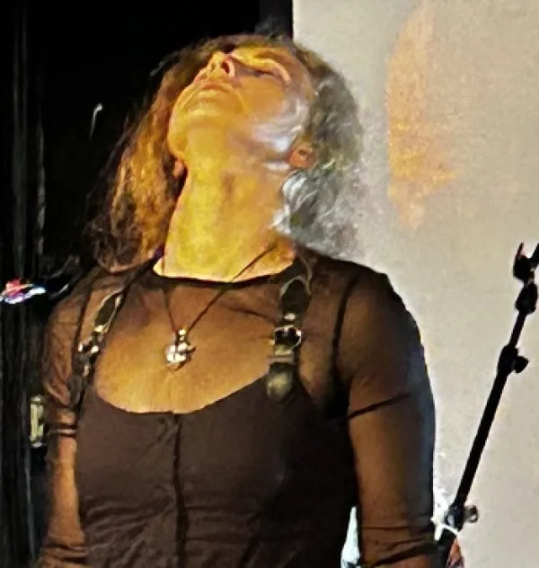 Blonde woman in black outfit with her head back and eyes closed