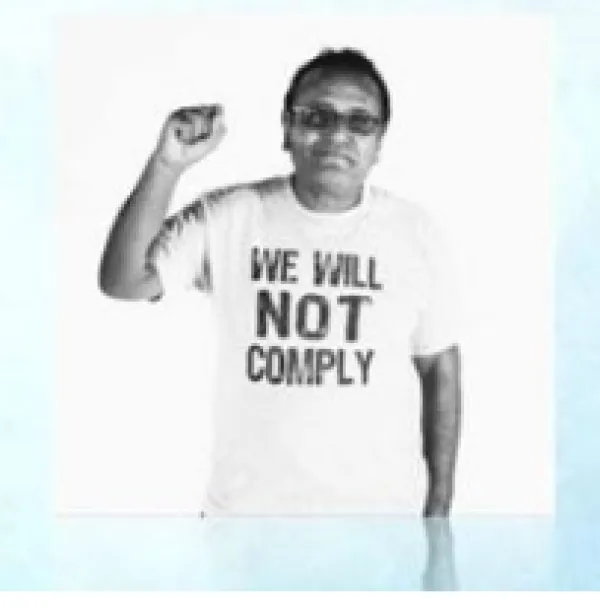 Latino man holding up a fist with a t-shirt saying we will not comply