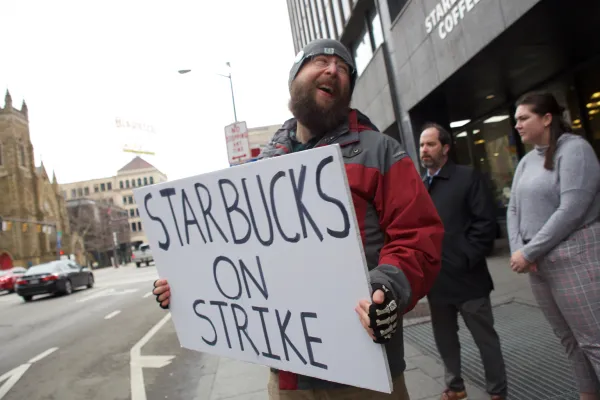 Guy outside Starbucks holding a sign saying Starbucks on strike