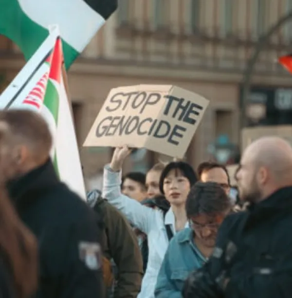 Woman holding sign at rally saying Stop the Genocide