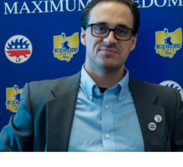 White man with black rimmed glasses in a suit coat