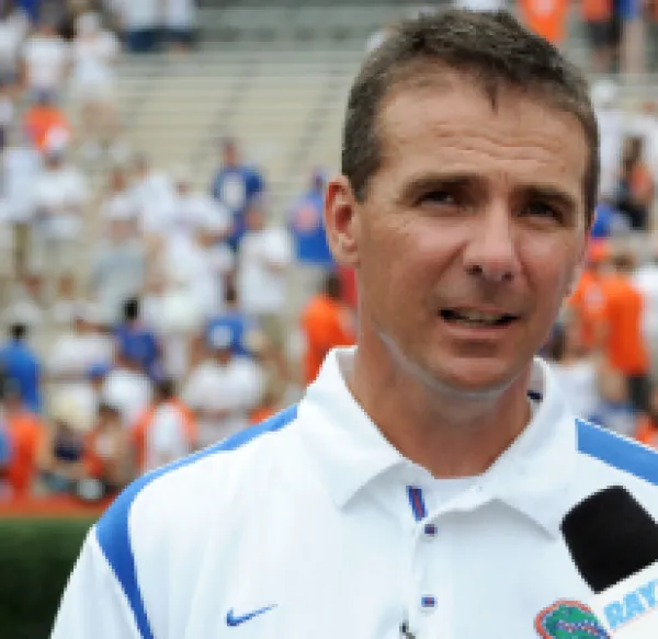 White guy in a white shirt with football stadium seats behind him