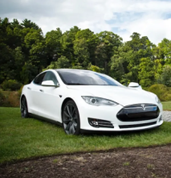 White sports car sitting outside on a green lawn with trees in the background