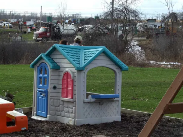 Backyard kid's playhouse with frackers working jsut behind it