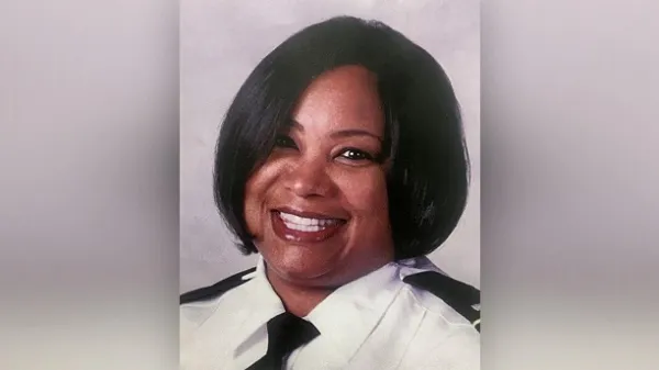 Head shot of black woman with short black hair smiling wearing a police uniform