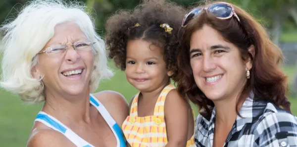 Young black girl with thirty-something white woman with brown hair and sunglasses on her head